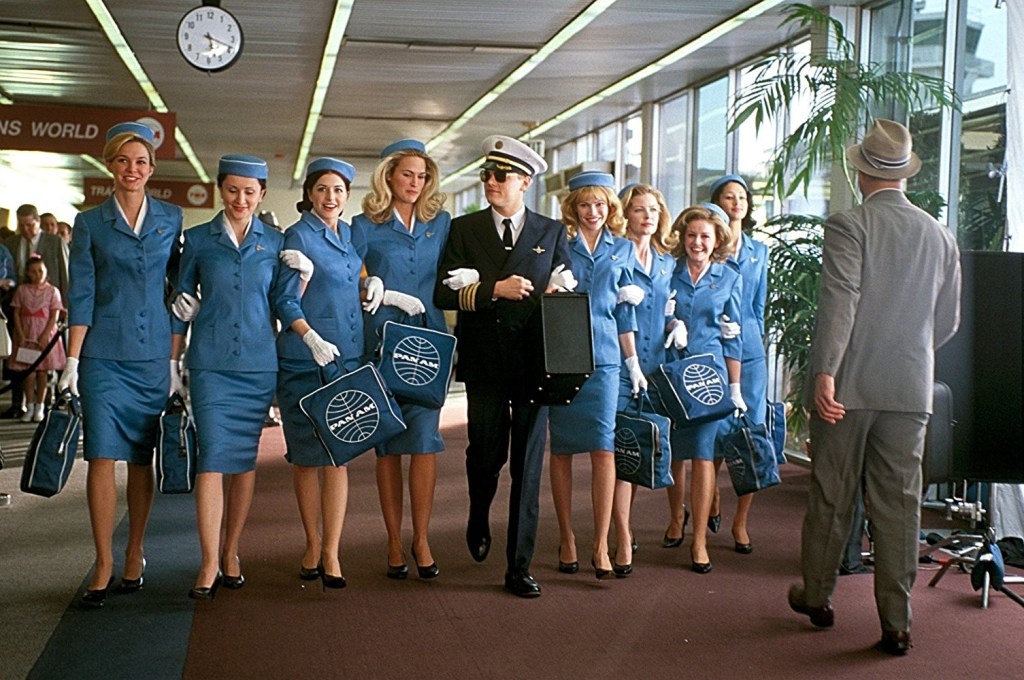 Pilot surrounded by 8 flight attendants